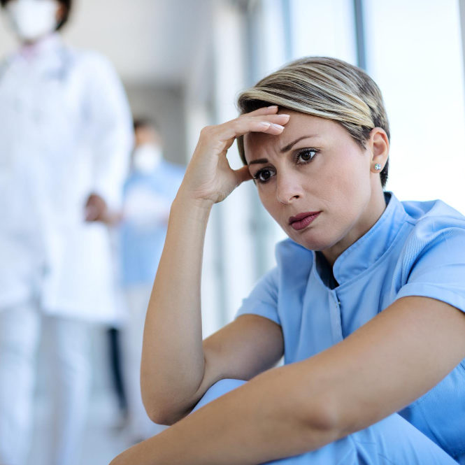 distraught-nurse-sitting-hallway-thinking-something